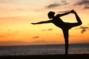 Yoga woman in serene sunset at beach doing king dancer pose. Med