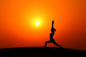 Silhouette of woman doing yoga meditation during sunset with nat